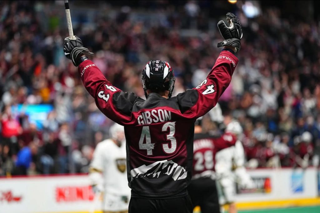 a lacrosse player celebrates, their hands in the air