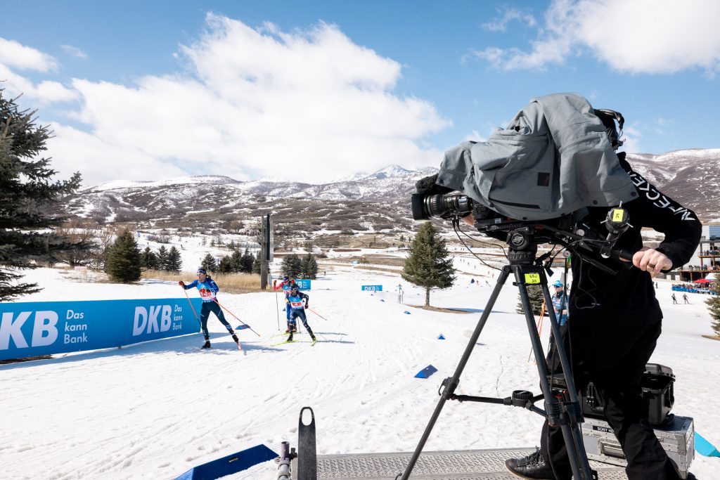 a camera person stands on the side of a biathlon race course